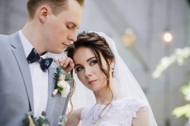 Gelin ve damat bahçede yürüyor. Ampullerden ve metal kapılardan oluşan bir çelengin önünde..