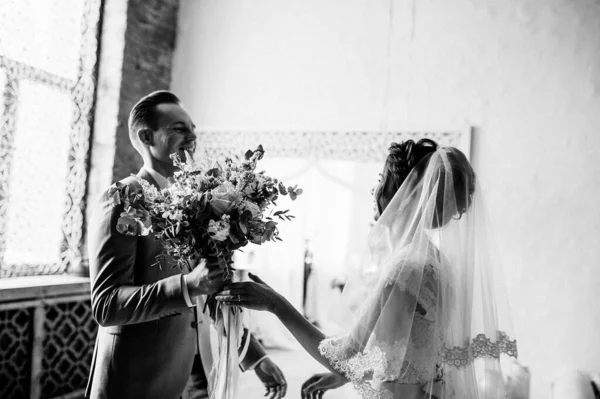 第一次见面 新郎拿着一束花走进了新娘的房间 粉色婚纱 灰色西服和时髦的花束 摩洛哥风格的房间 黑白照片 — 图库照片