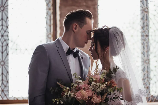 第一次见面 新郎拿着一束花走进了新娘的房间 他们拥抱和亲吻 粉色婚纱 灰色西服和时髦的花束 摩洛哥风格的房间 — 图库照片