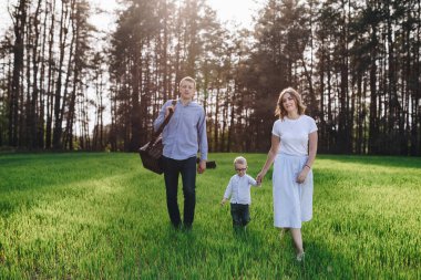 Aile ormanda bir pikniğe gidiyor. Anne, baba, oğul. Yaz yürüyüşü. Piknik seti. Köpek. Gözlüklü çocuk. Mavi kıyafetler. Güzel aile..