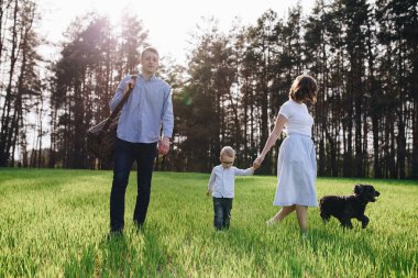 Aile ormanda bir pikniğe gidiyor. Anne, baba, oğul. Yaz yürüyüşü. Piknik seti. Köpek. Gözlüklü çocuk. Mavi kıyafetler. Güzel aile..