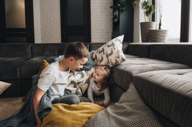 Pijamalı bir aile. Erkek ve kız kardeş. Yeni yıl havası. Eğlenceli fotoğraf. Yerde yastıklarla oyna. Gri iç kısım.