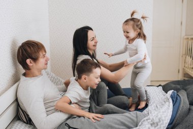 Evde pijamalı bir aile. Kızı ve oğlu. Sabah uyanırsın. Yatak odasında sarılıp öpüşüyorlar..