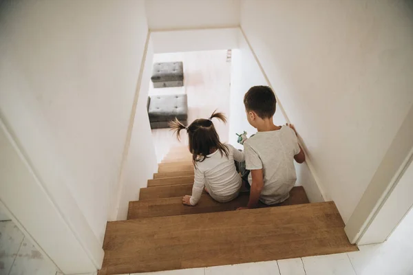 Children play at home on the stairs. Gray homewear. Son and daughter Brother and sister. Sit on the steps.