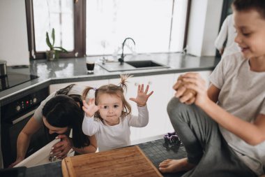 Aile mutfakta zencefilli kurabiye hazırlıyor. Baba, anne, oğul, kız, erkek ve kız kardeş. Diz hamuru, kurabiye kesiciler, yeni yıl, Noel, tatil yemeği. Gri ev kıyafeti.