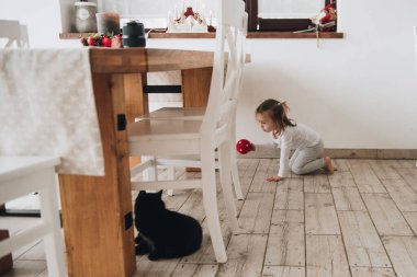 Büyük bir evde aile. Yaşam tarzı ev konforu. Evdeki çocuklar. Kız siyah bir kediye yetişiyor. Evcil hayvan.