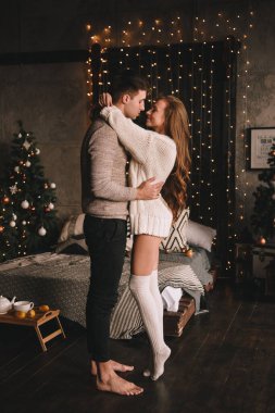 Yatak odasındaki yatakta bir çift. İçi karanlık. Yeni yıl ve Noel. Öpücükler ve sarılmalar. Sevgi. Beyaz kazak ve yüksek çoraplar. Romantik bir buluşma. Randevu aşıkları..