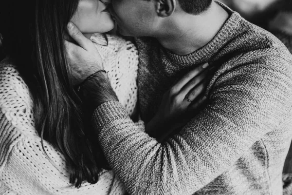 Black and white photo. Couple on the bed in the bedroom. Dark interior. New Year\'s and Christmas. Hugs and kisses. Love. White sweater and high socks. Romantic meeting. A date lovers.