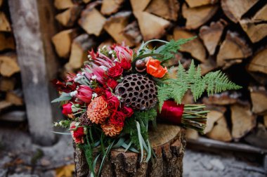 Orijinal sonbahar gelini buketi kütüğün üzerinde yatıyor.