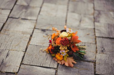 Damat, iplik, akçaağaç yaprakları, fisalis ve kasımpatı dolu orijinal sonbahar gelin buketini tutuyor.