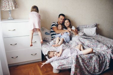 Çocuklar ve ebeveynler sabahları yatakta dinlenirler. Çocuklar şımarır, sarılırlar. İkizler. Ağaç kızları.