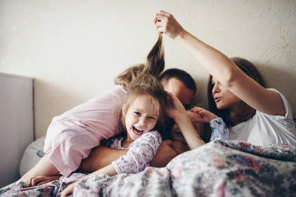 Children and parents rest in the morning in bed. Children indulge, hug. Twins. Three daughters.