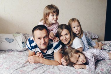 Çocuklar ve ebeveynler sabahları yatakta dinlenirler. Çocuklar şımarır, sarılırlar. İkizler. Ağaç kızları.