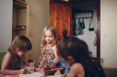 Üç kız kardeş çocuk odasında keçeli kalemle resim yapıyor. İkizler..