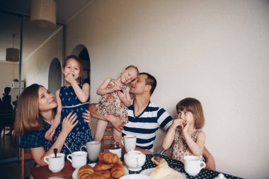 Aile kahvaltısı. Ailesi olan kızlar masaya oturur, kruvasan, kurabiye yer, çay içerler..