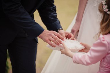 İlkbaharda klasik düğün. Tören. Küçük kız yüzük taşıyor. Damat yüzüğü yastıktan çıkarır..