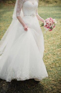 Pembe buketli beyaz elbiseli gelin. Baharda düğün.