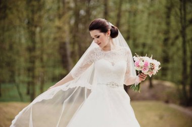 Pembe buketli beyaz elbiseli gelin. Baharda düğün.