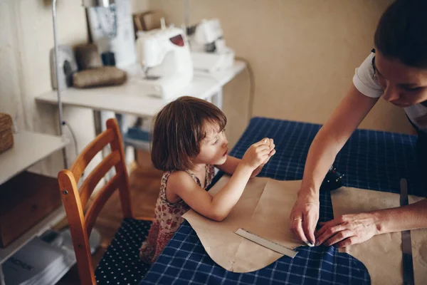 Mom and daughter sew clothes together. Pattern dress.