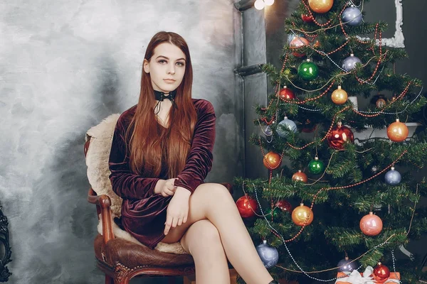 Mädchen sitzt neben einem Weihnachtsbaum — Stockfoto