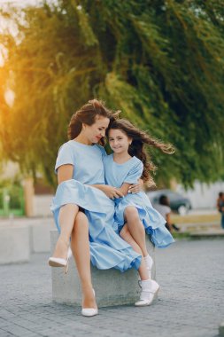 Anne ve kızı aynı elbiseler bir parkta oturuyor
