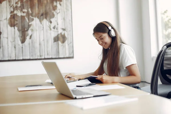 Genç öğrenci masada oturuyor ve dizüstü bilgisayarını kullanıyor.
