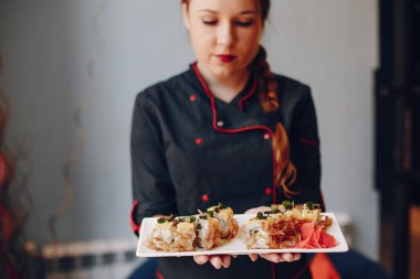 Kafede suşi tutan kişinin yakın çekimi.