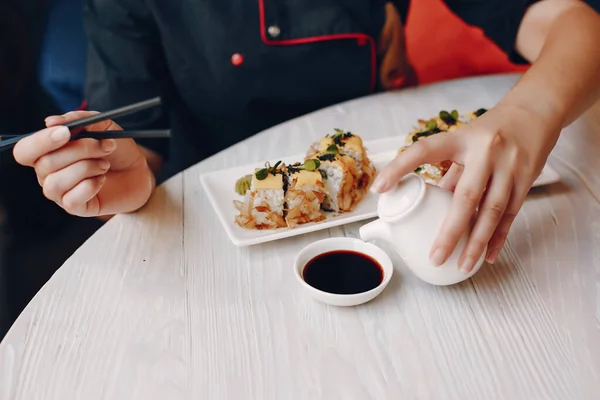 Wanita duduk di kafe di meja dan makan sushi — Stok Foto