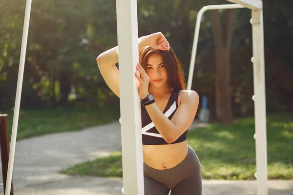 Deportiva chica en un negro superior de formación en un parque de verano — Foto de Stock