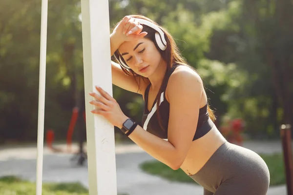 여름 공원에서 헤드폰을 사용하여 훈련받고 있는 스포츠 소녀 — 스톡 사진