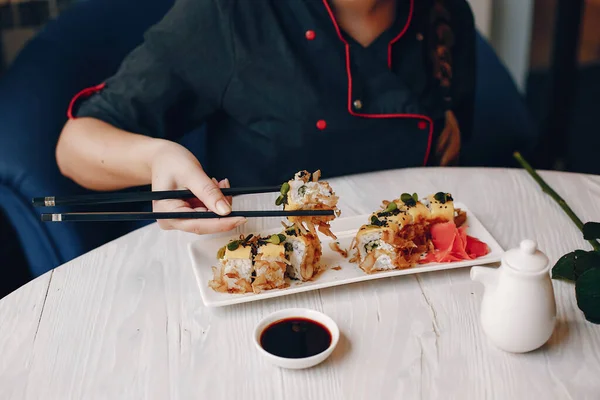 Wanita duduk di kafe di meja dan makan sushi — Stok Foto