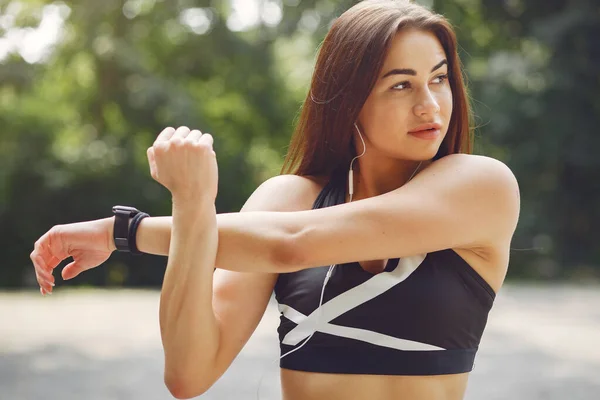 Treinamento de meninas de esportes com fones de ouvido em um parque de verão — Fotografia de Stock