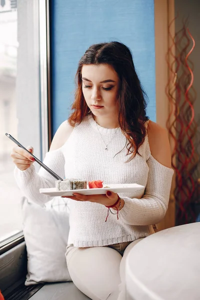 Kobieta siedząca przy stole i jedząca sushi w kawiarni — Zdjęcie stockowe