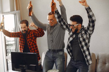 Bir grup taraftar televizyonda bir futbol maçı izliyorlar.