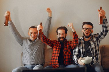 Bir grup taraftar televizyonda bir futbol maçı izliyorlar.