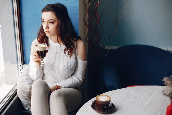 하얀 스웨터를 입고 카페에 혼자 앉아 있는 여자 — 스톡 사진