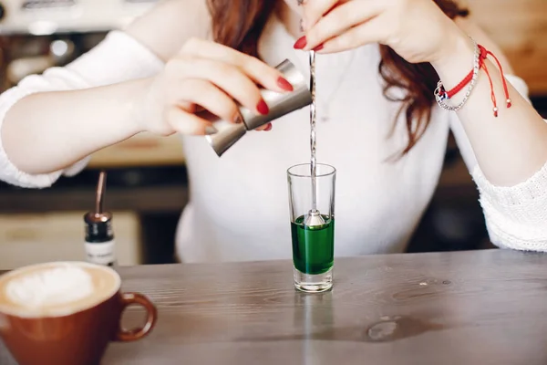 Женщина в белом свитере заливает зеленый сироп в стекло — стоковое фото