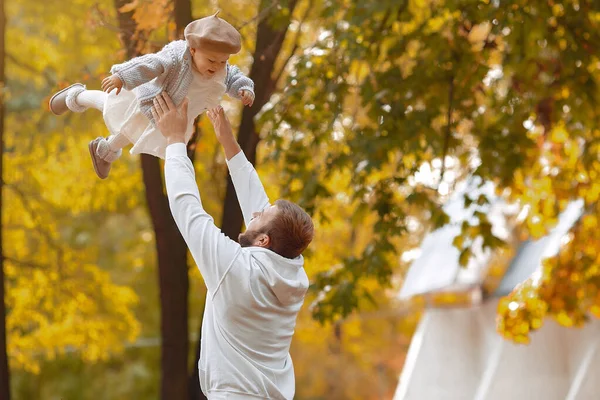 Jóképű apa szürke pulóverben játszik a kislányával egy őszi parkban. — Stock Fotó