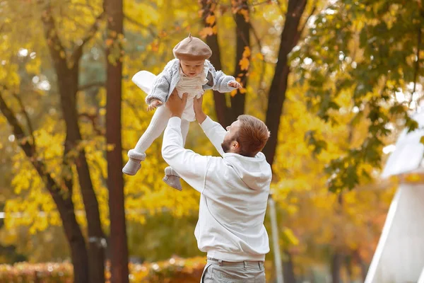 Bonito pai em uma camisola cinza brincando com a filhinha em um parque de outono — Fotografia de Stock