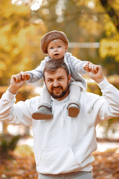 Jóképű apa szürke pulóverben játszik a kislányával egy őszi parkban. — Stock Fotó