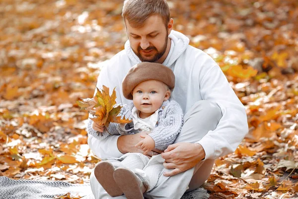 Bonito pai em uma camisola cinza brincando com a filhinha em um parque de outono — Fotografia de Stock