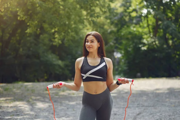 Treinamento de meninas de esportes com corda de salto em um parque de verão — Fotografia de Stock