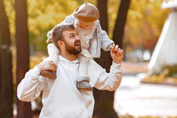 Bonito pai em uma camisola cinza brincando com a filhinha em um parque de outono — Fotografia de Stock