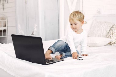 Yatakta dizüstü bilgisayarla oynayan şirin bir çocuk.