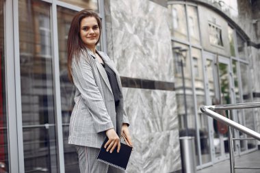 Şık bir iş kadını şehirde çalışıyor ve defteri kullanıyor.