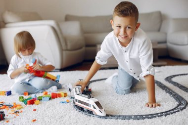Çocuklar oyun odasında lego ve oyuncak trenle oynuyorlar.