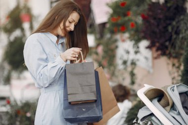 Şehirde alışveriş çantası taşıyan mavi elbiseli bir kadın.