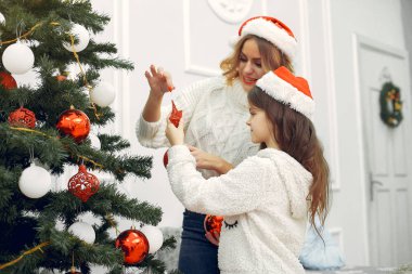 Anne ve tatlı kızı Noel ağacının yanında duruyor.