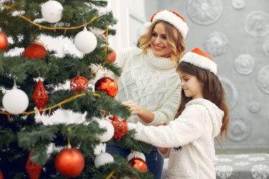 Anne ve tatlı kızı Noel ağacının yanında duruyor.