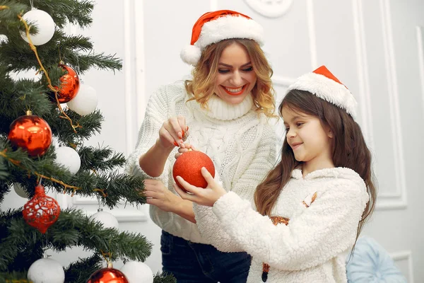 Anne ve tatlı kızı Noel ağacının yanında duruyor.